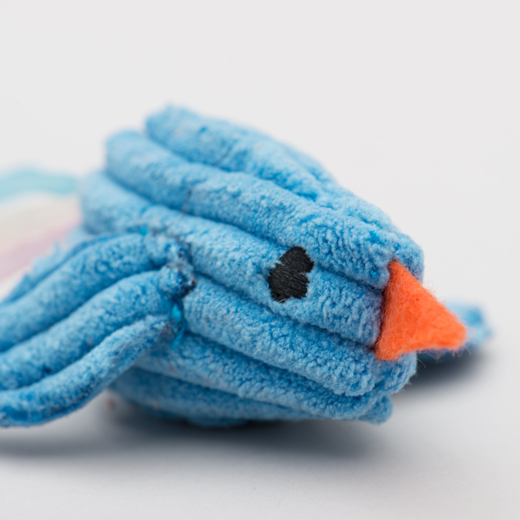 Blue bird plush cat toy with an orange beak on a white background.