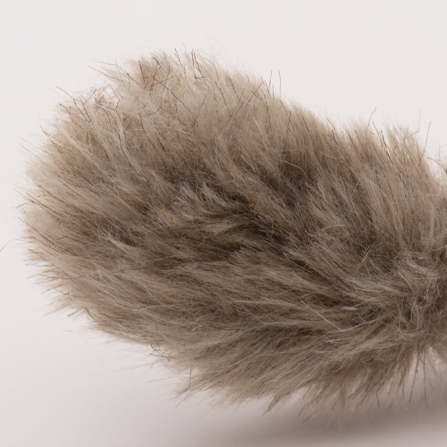 Close-up of a fluffy brown squirrel tail cat toy on a light background.