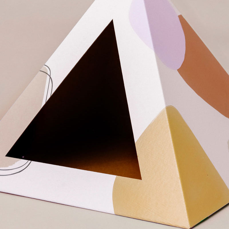 Geometric cat pyramid with black, gold, and pink colors on a beige background.