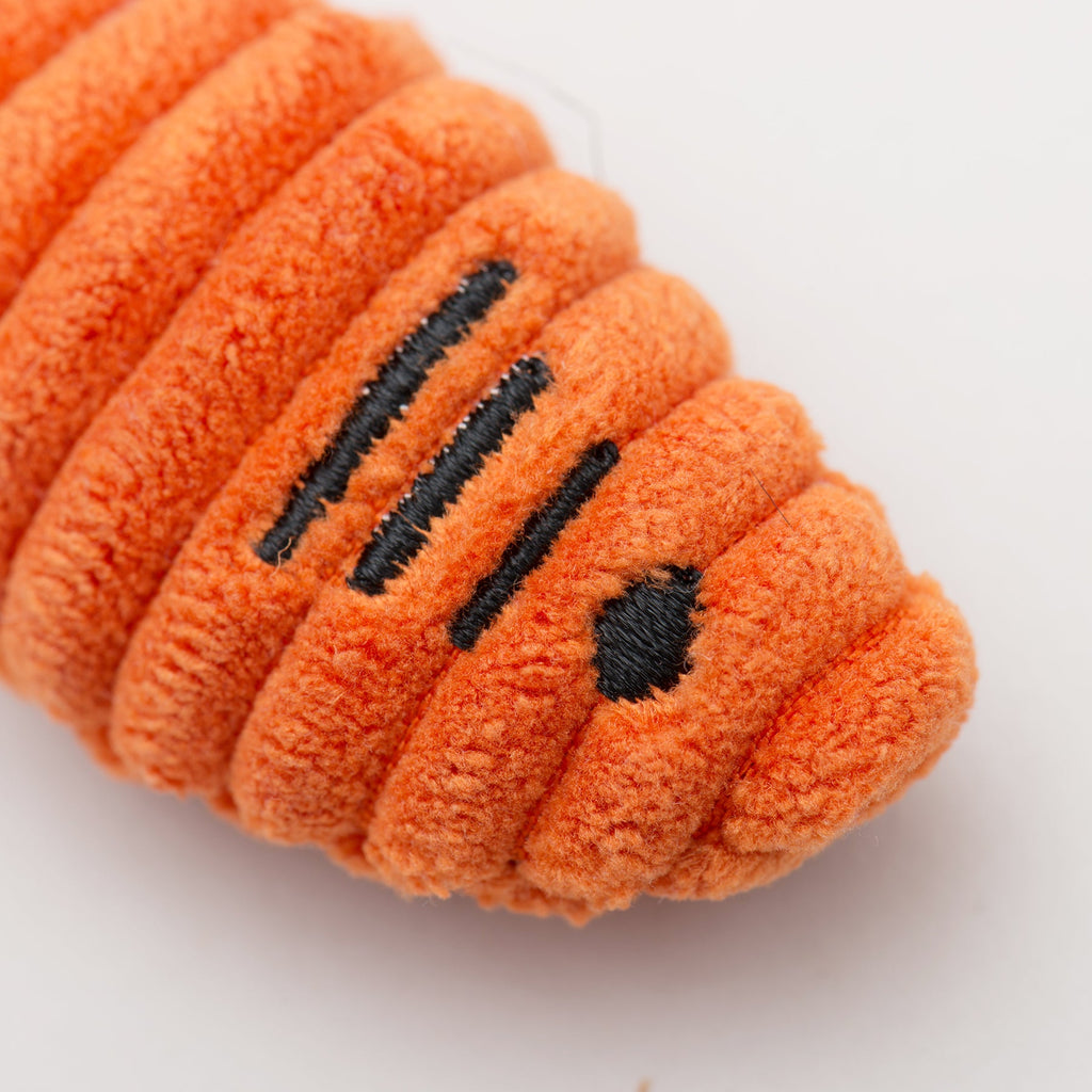Close-up of an orange plush cat fish toy with black paw prints on a white background.
