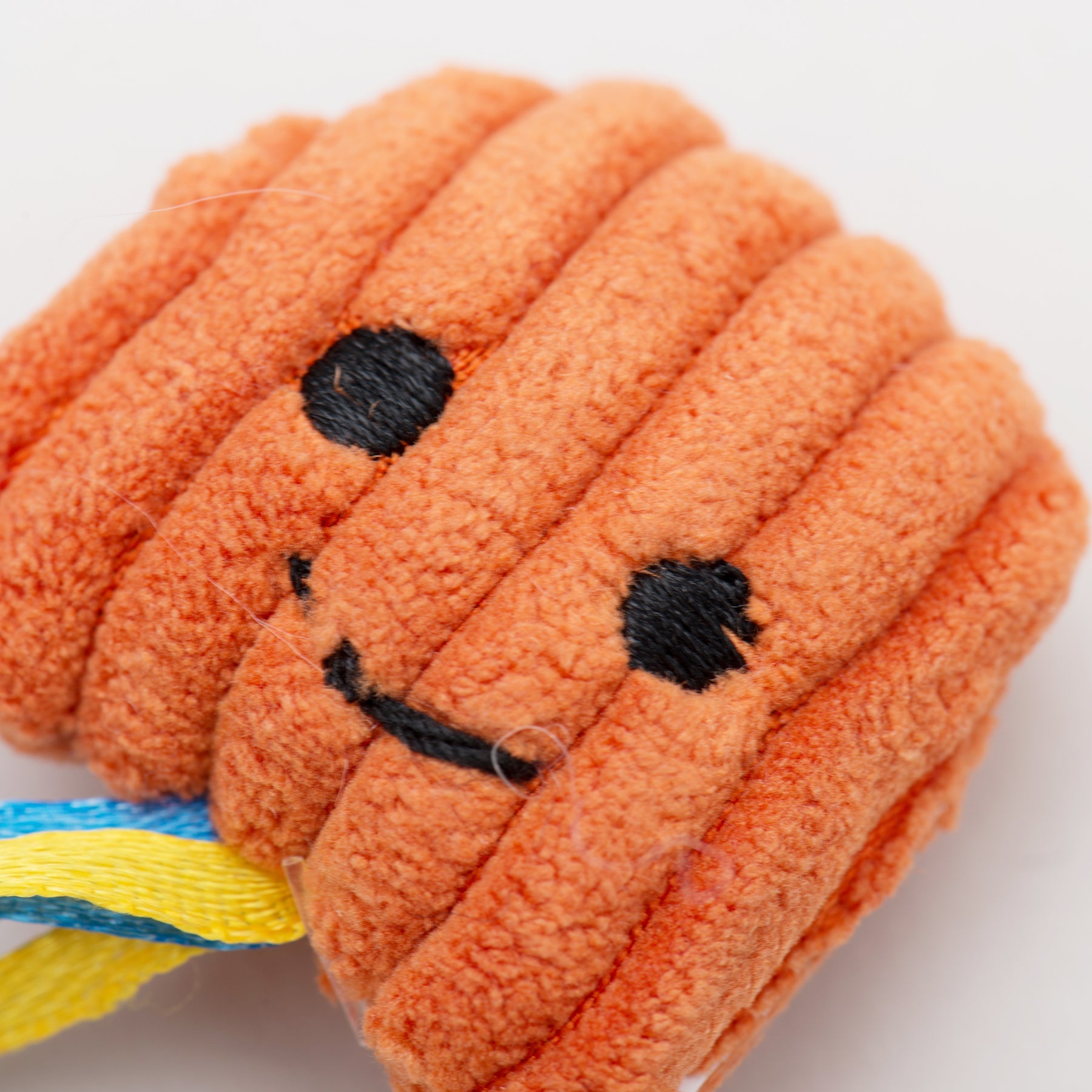Orange plush cat rope toy with a smiley face on a white background.