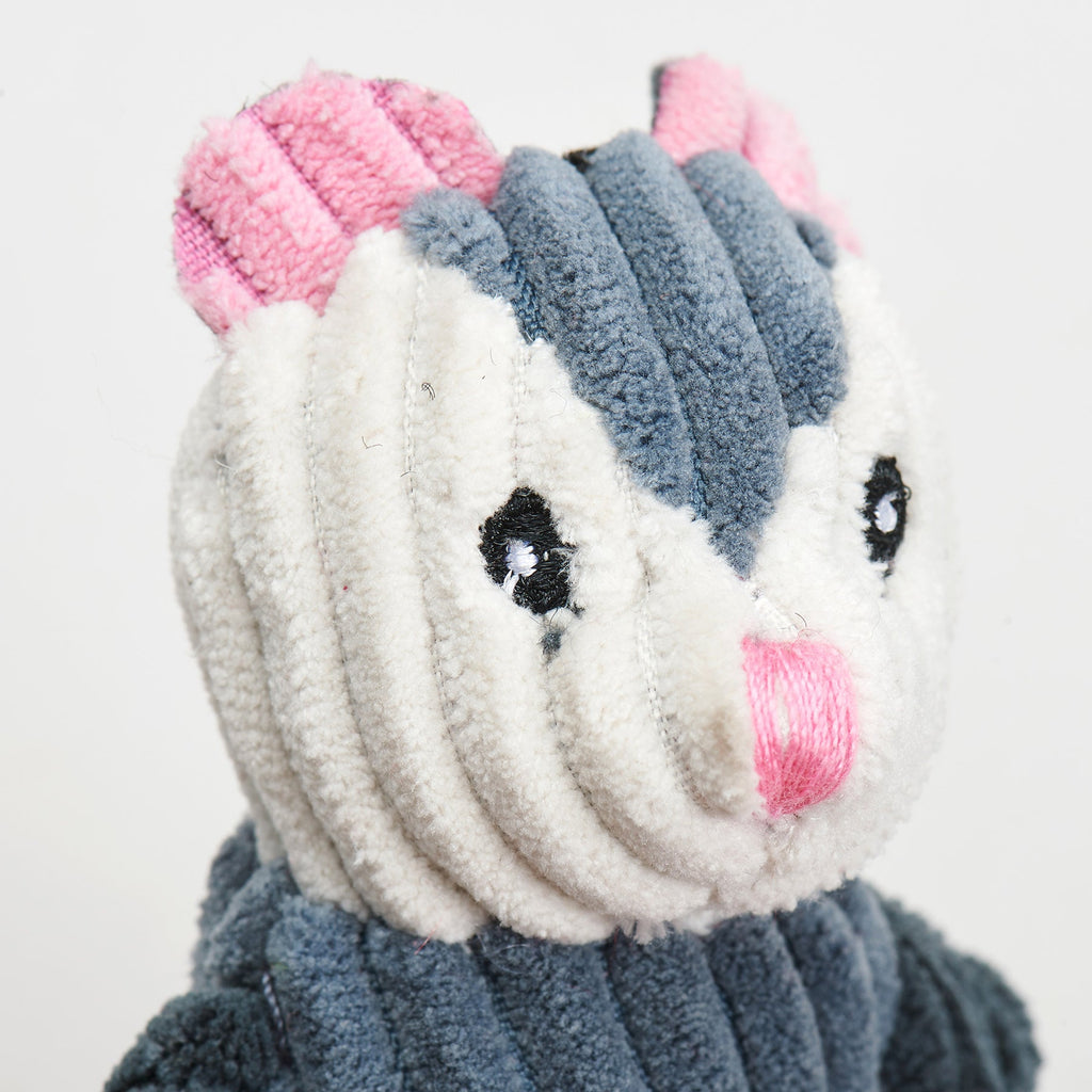 Close-up of a opossum plush toy with pink ears and a gray body on a white background.