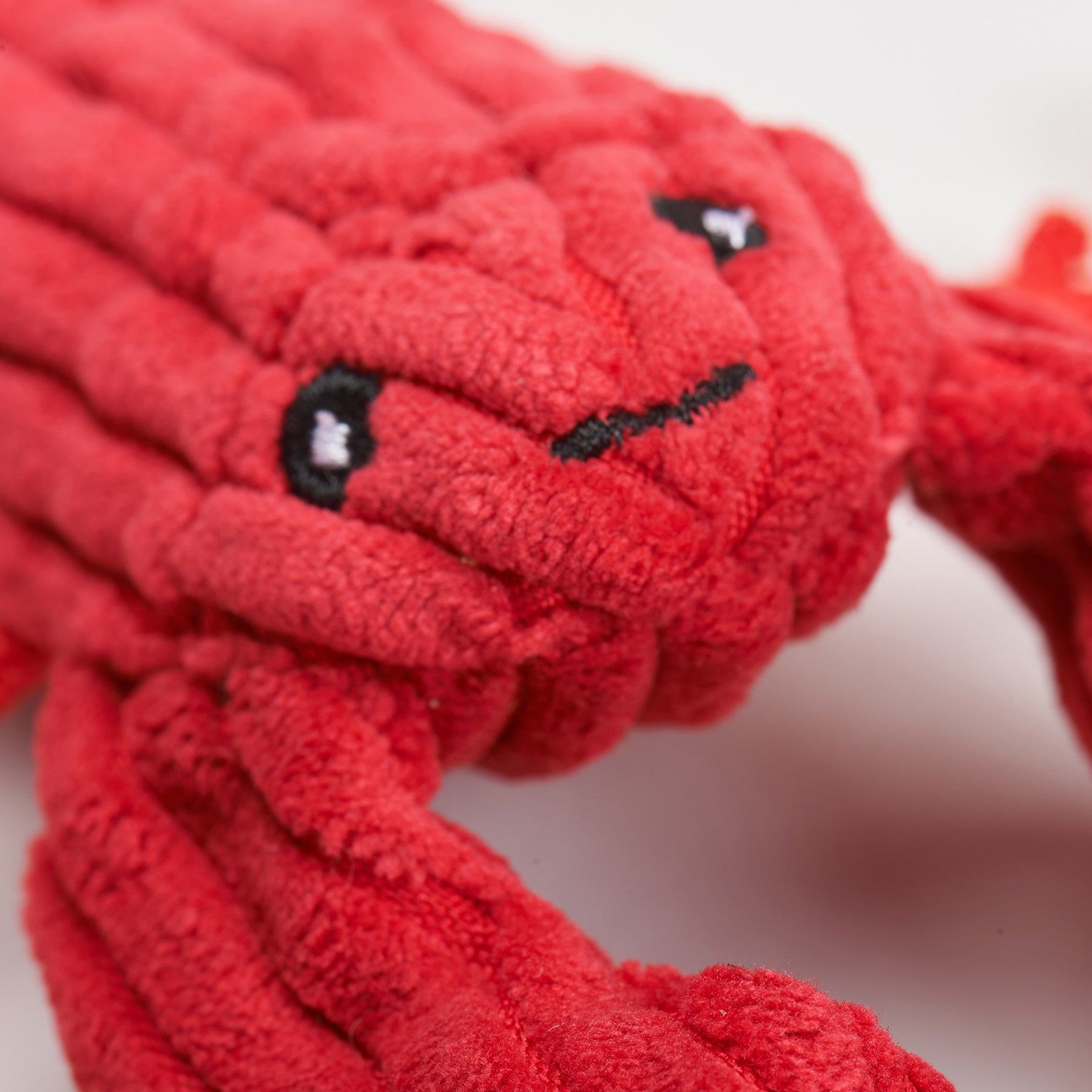 Close-up of a red plush toy resembling a dragon on a white background.