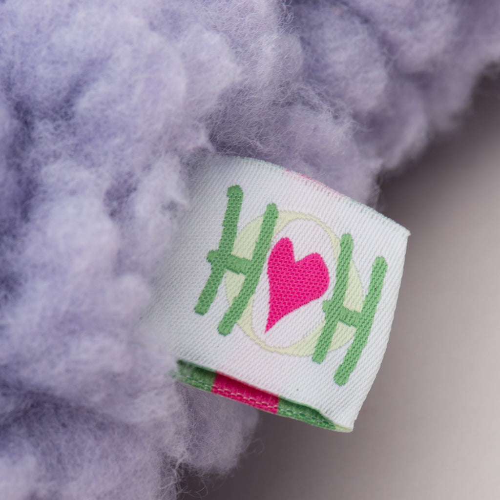 Close-up of a ribbon with 'HH' and a heart on it, surrounded by fluffy material.