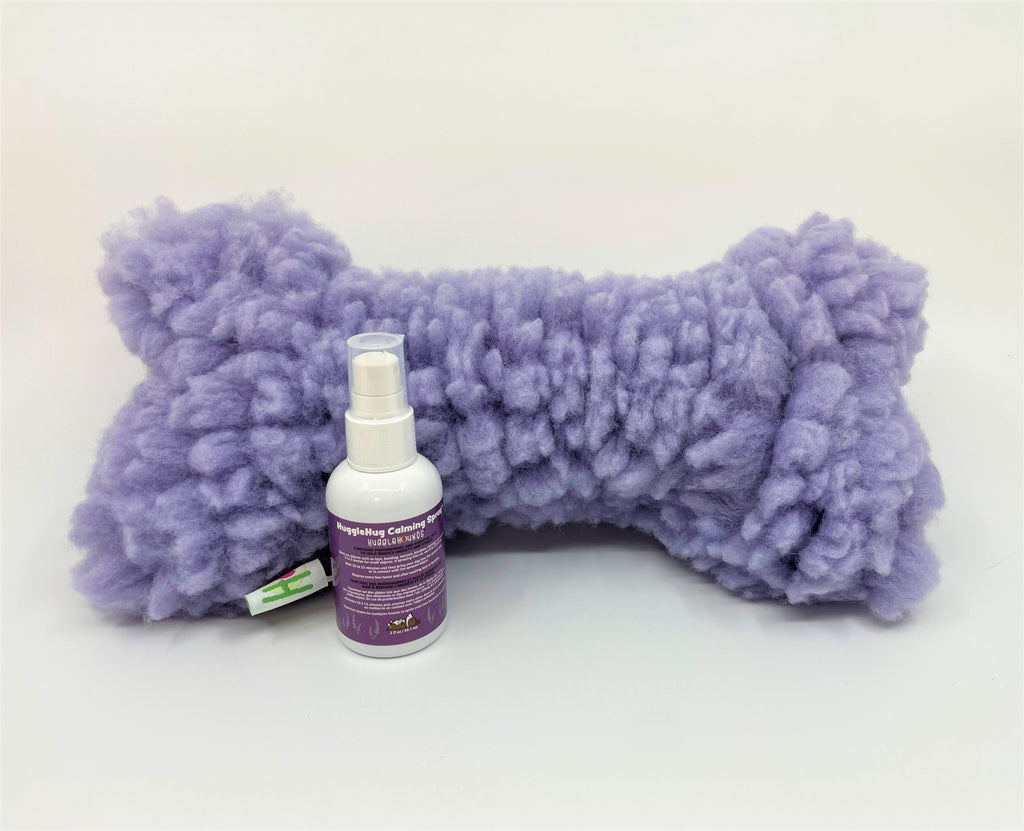 Purple textured plush dog bone toy and spray bottle on a white background.