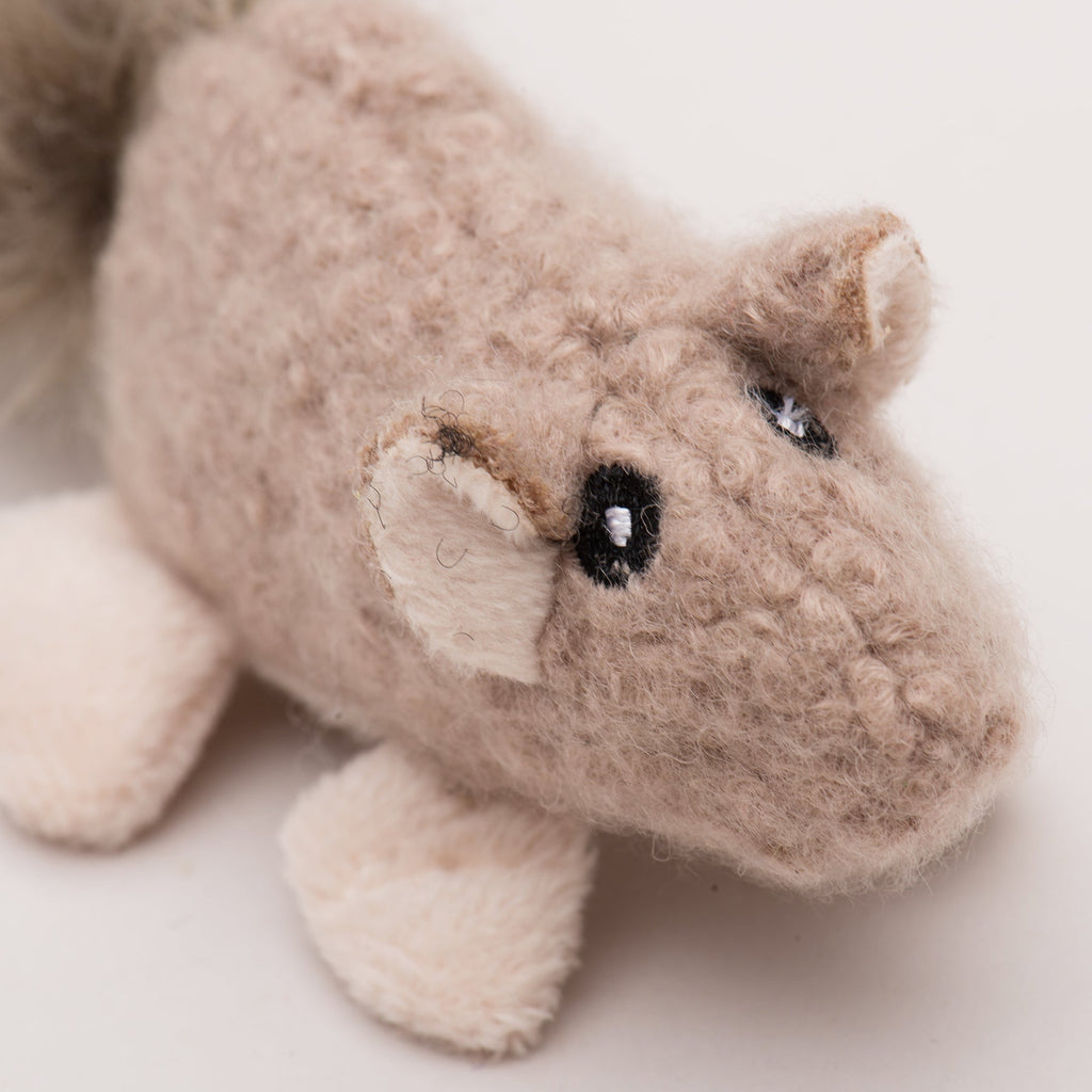 Close-up of a beige squirrel plush cat toy on a light background.